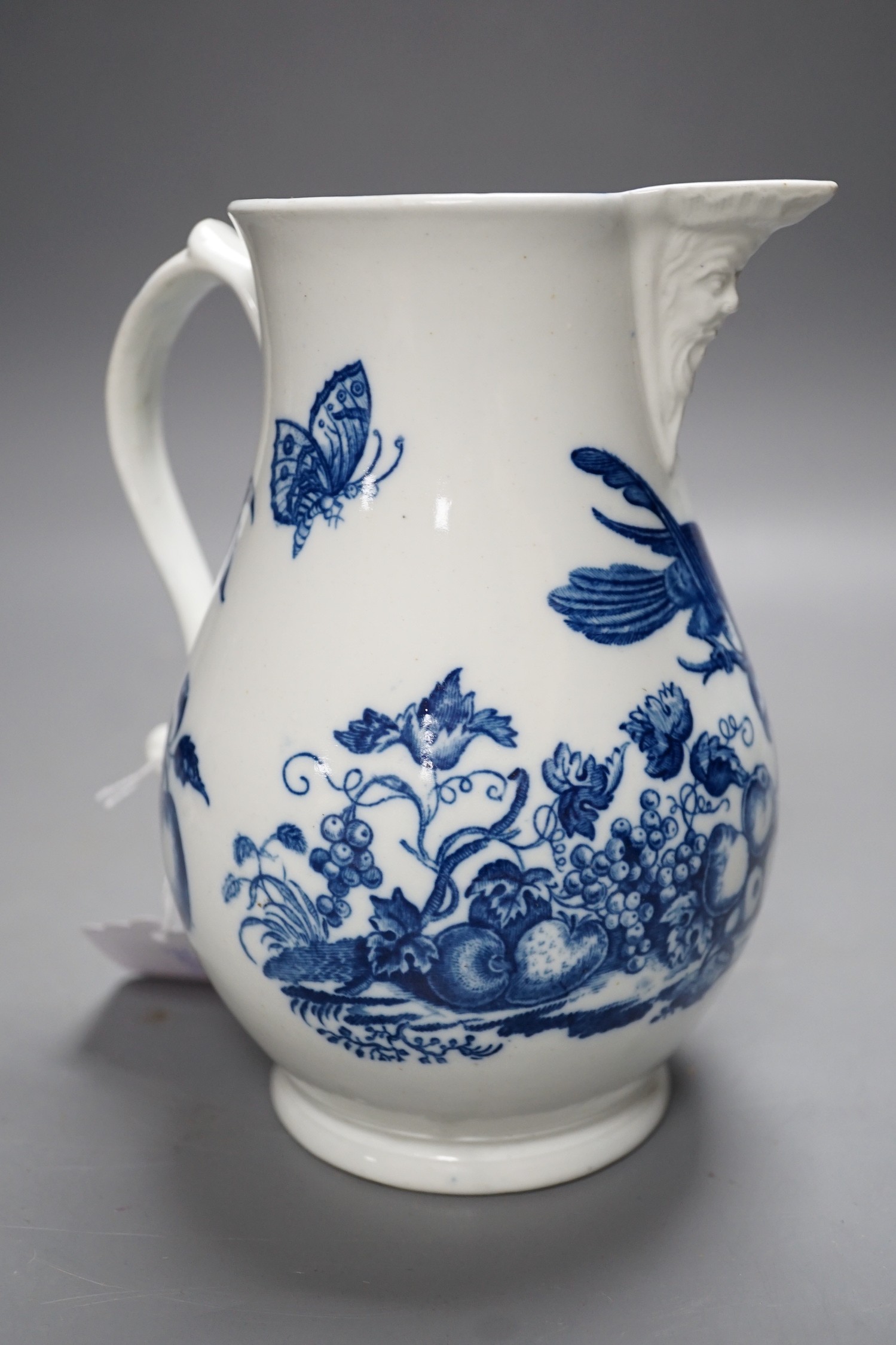 A Caughley baluster mask jug printed in underglaze blue with the 'parrot pecking fruit', 18.5cms high